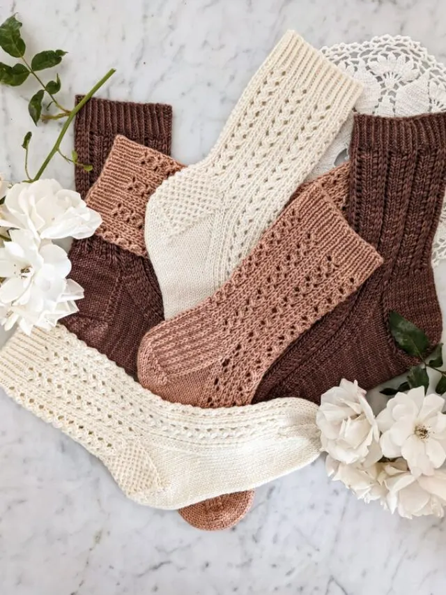 A jumbled pile of three pairs of lacy socks in cream, pink, and brown.