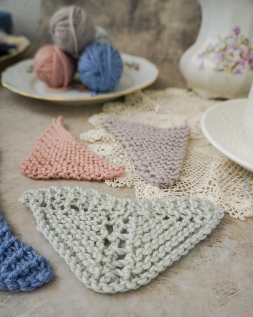 A close up on a pale green mini triangle shawl. This shows a symmetrical triangle shawl with traditional increases on the right side only, resulting in a deeper center point.