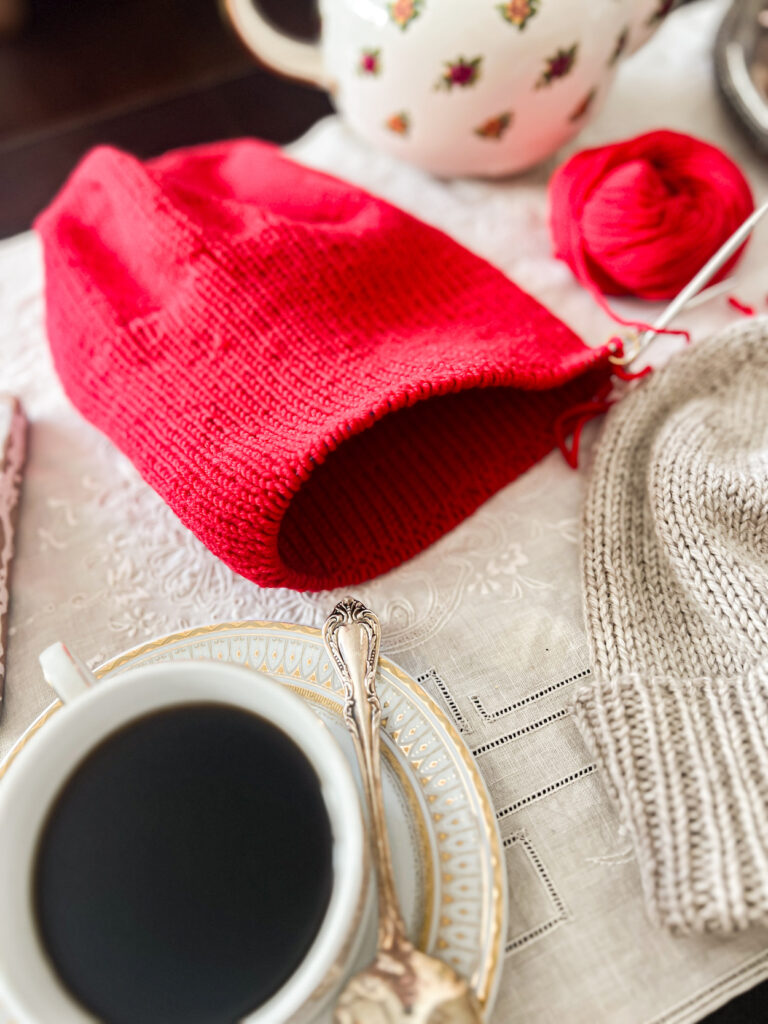 A close-up on the ribbed brim in progress on a red knit hat.